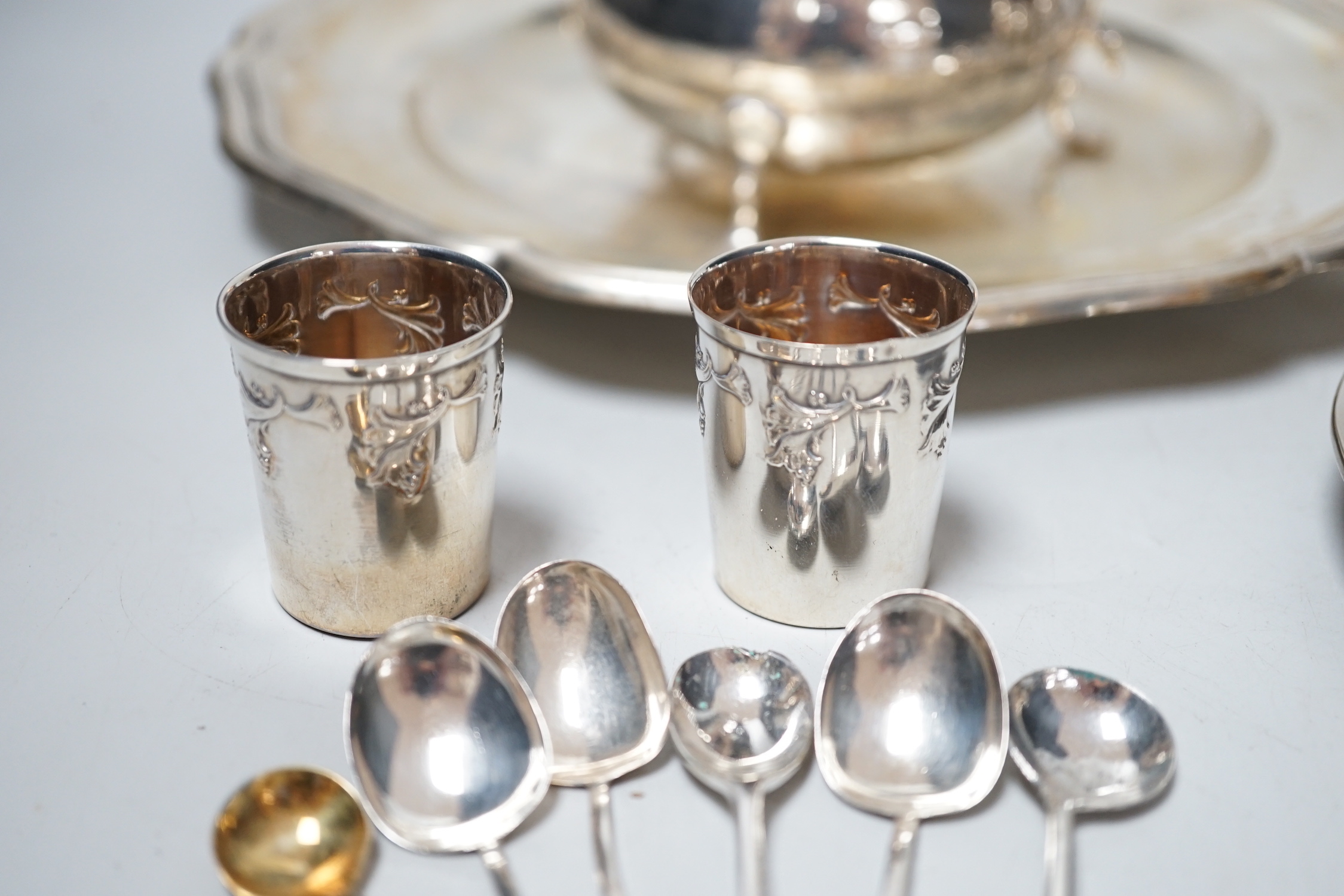 An 800 white metal plate, 24.8cm, a George V silver two handled bowl, a silver ashtray, six silver condiments, two 800 tots and minor plated ware, 24.1oz.